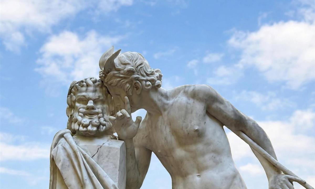 Statue de marbre sur fond de ciel bleu : un jeune homme murmure à l'oreille d'un buste barbu
